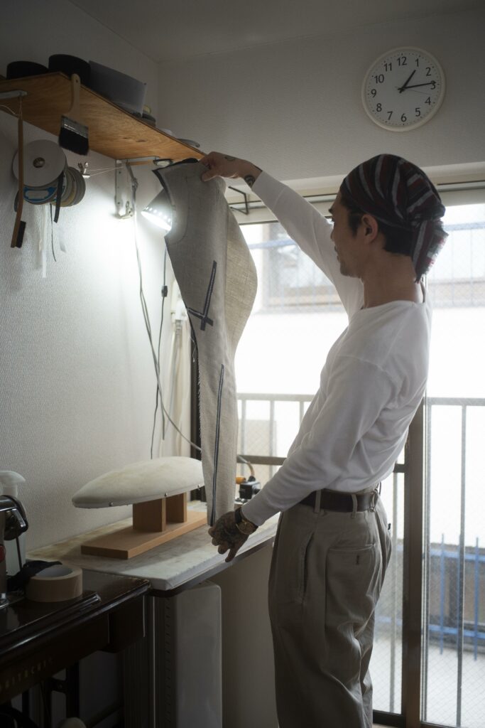 Artisan tailleur dans son atelier tenant une pièce de vêtement en cours de confection : comprendre le travail réel et les métiers