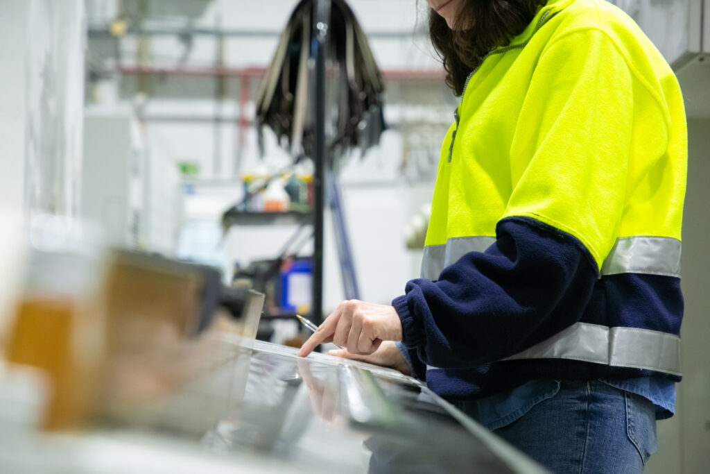 Opératrice en tenue de sécurité à son poste de contrôle dans une usine : organisation du travail et santé des salariés en production
