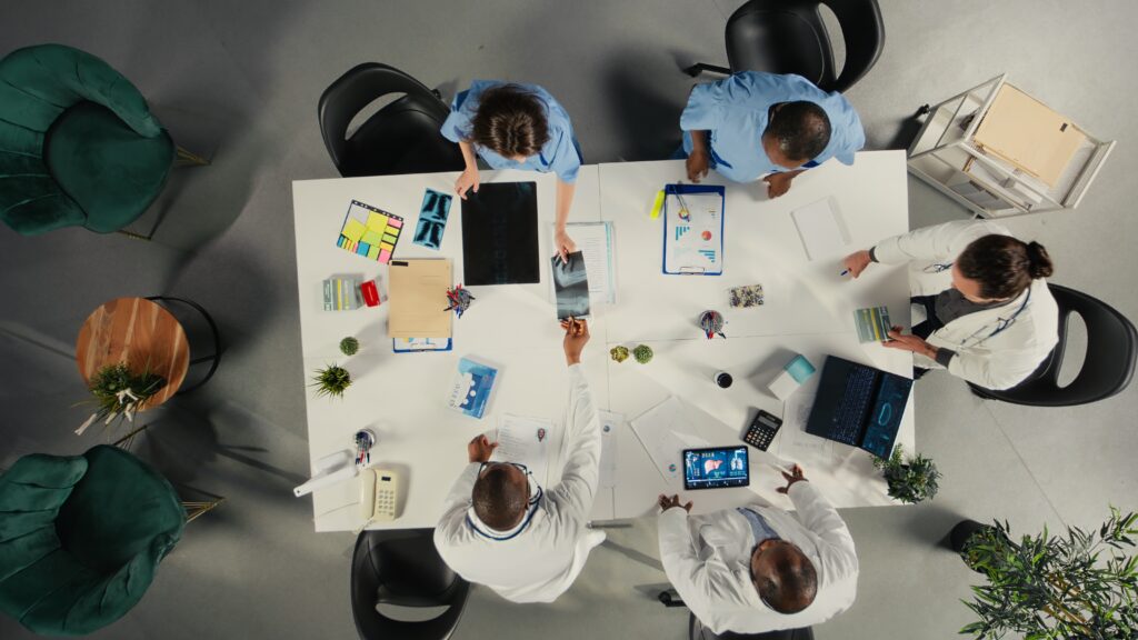 Réunion d'équipe autour d'une table de travail, vue de dessus : accompagnement des organisations face aux changements par une psychologue du travail